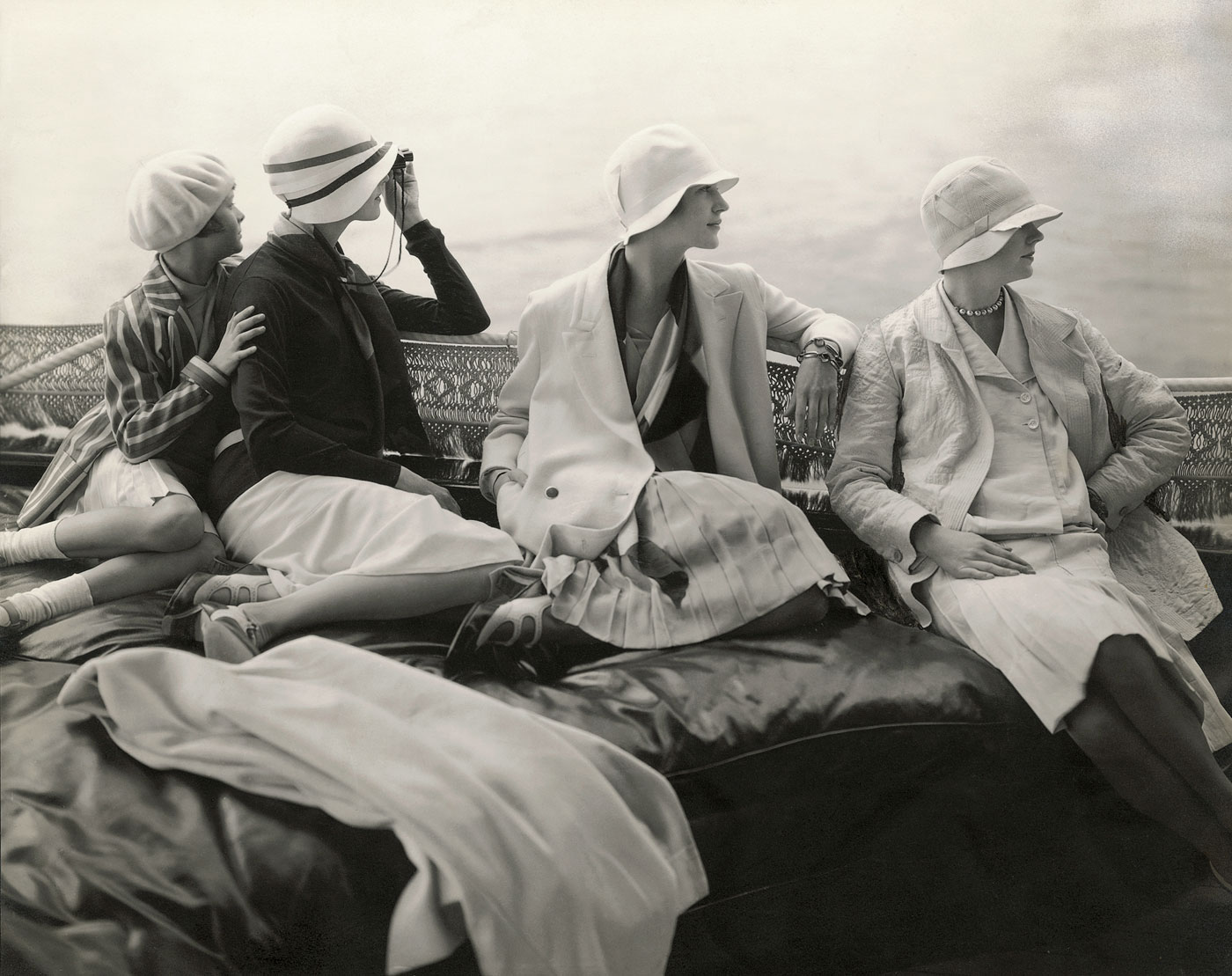 On George Baher’s yacht. June Cox wearing unidentified fashion; E. Vogt wearing fashion by Chanel and a hat by Reboux; Lee Miller wearing a dress by Mae and Hattie Green and a scarf by Chanel; Hanna-Lee Sherman wearing unidentified fashion, photo by Edward Steichen, 1928