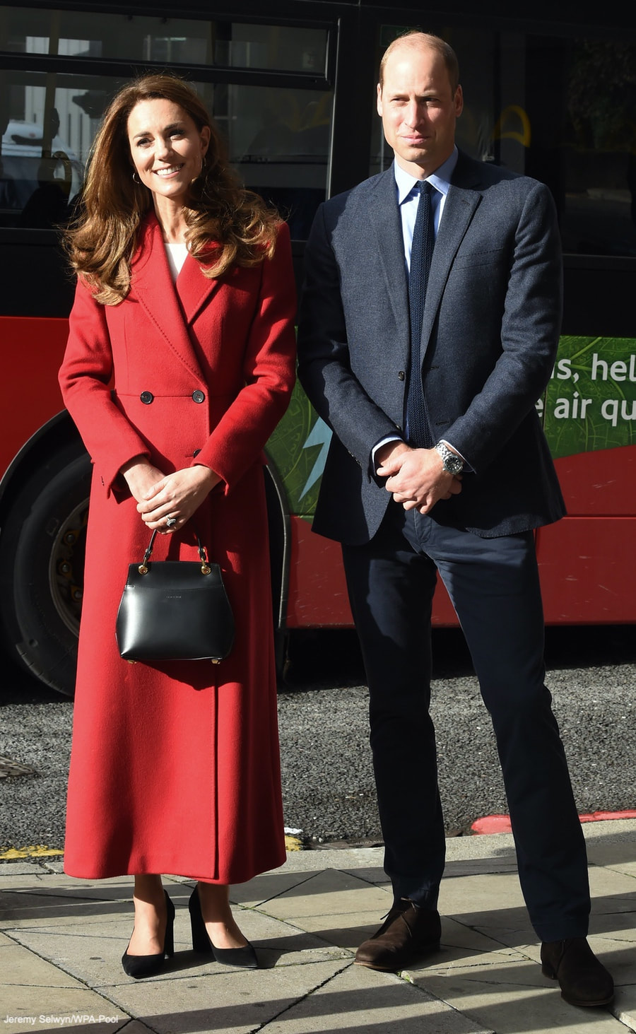Kate Middleton Duchess of Cambridge custom made/bespoke Alexander McQueen red double breast full length coat with peak lapel for Hold Still photography project at Waterloo Station in London 