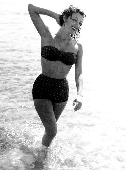 Elegant style icon wardrobe essentials: Ava Gardner in swimwear, Ava Gardner in two piece bikini in polka dot print at beach in Spain, 1951