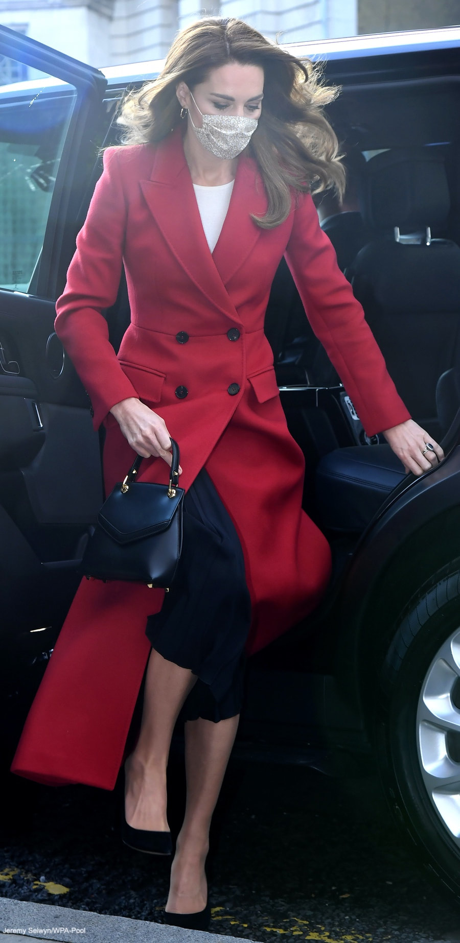 Kate Middleton Duchess of Cambridge custom made/bespoke Alexander McQueen red double breast full length coat with peak lapel for Hold Still photography project at Waterloo Station in London 