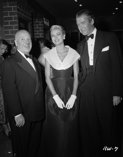 Elegant style icon wardrobe essentials: Grace Kelly in black dress, accompanied by Alfred Hitchcock and James Stuart, Premiere of Rear Window, 1954