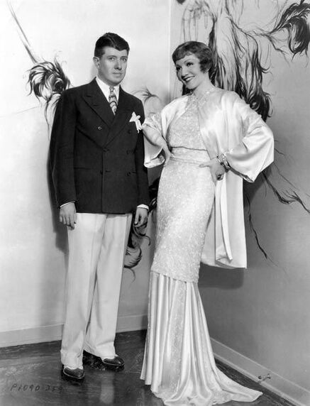 Travis Banton with Claudette Colbert, who is wearing his design
