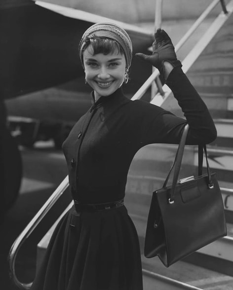 Elegant style icon wardrobe essentials: Audrey Hepburn in little black dress, Heathrow Airport in London, 21 May 1953.